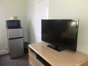 A microwave and refrigerator behind a TV