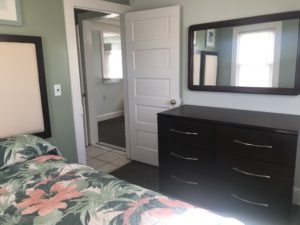 A bedroom with an open door next to a dresser